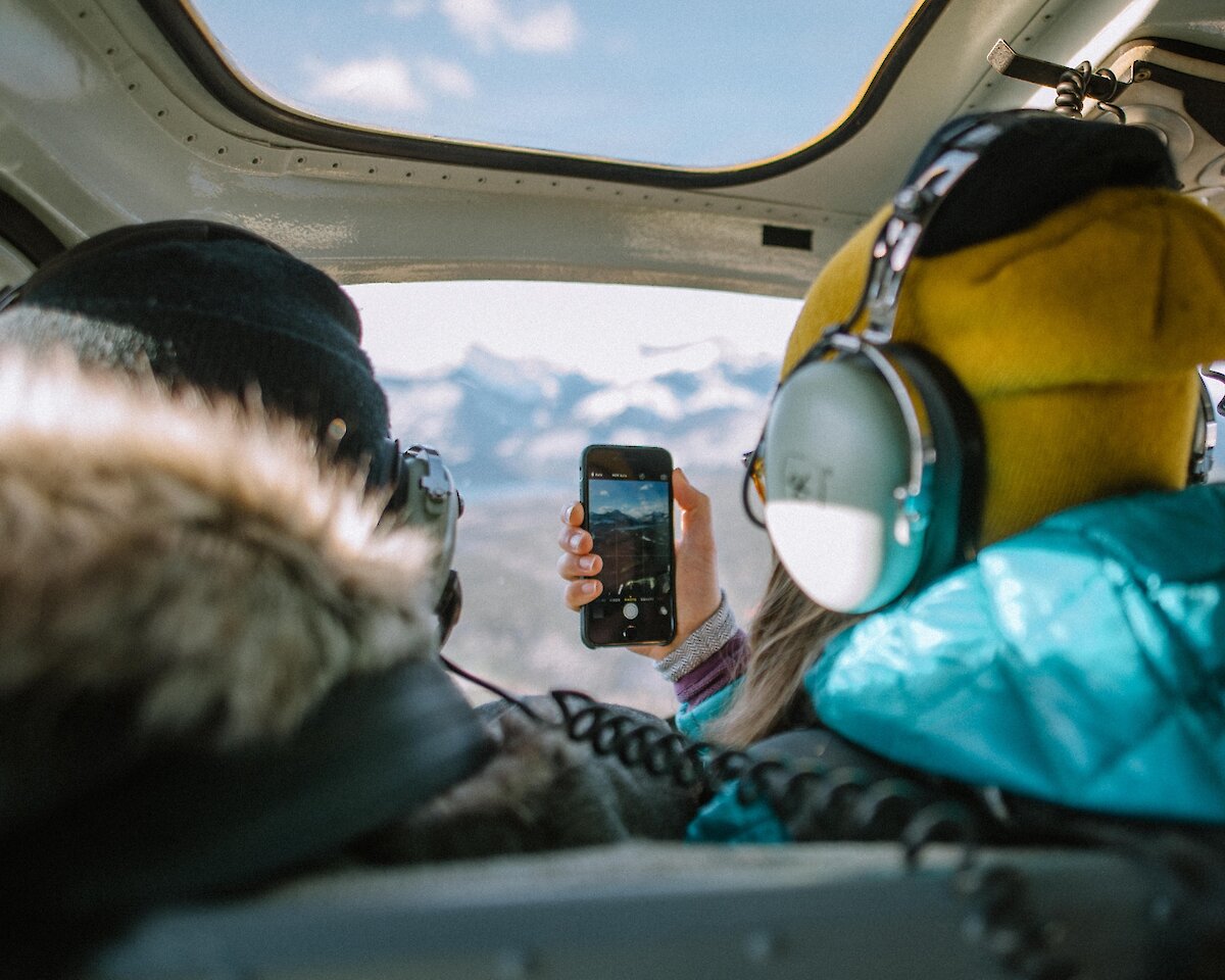 A couple taking photos during a winter helicopter flight