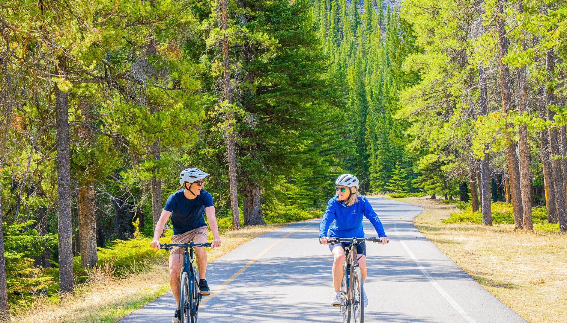 A couple cycling next to Lake Minnewanka in Banff