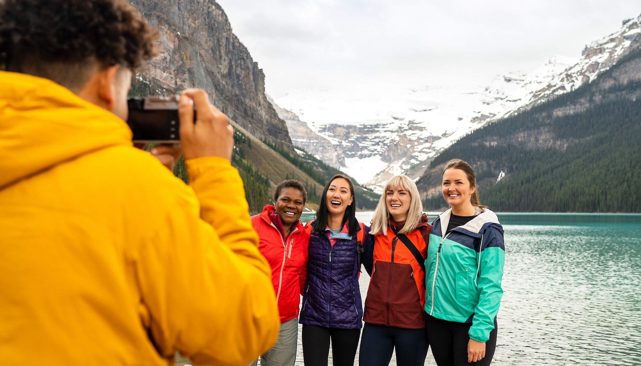 A group of friends getting a photo on Lake Louise Lake Shore