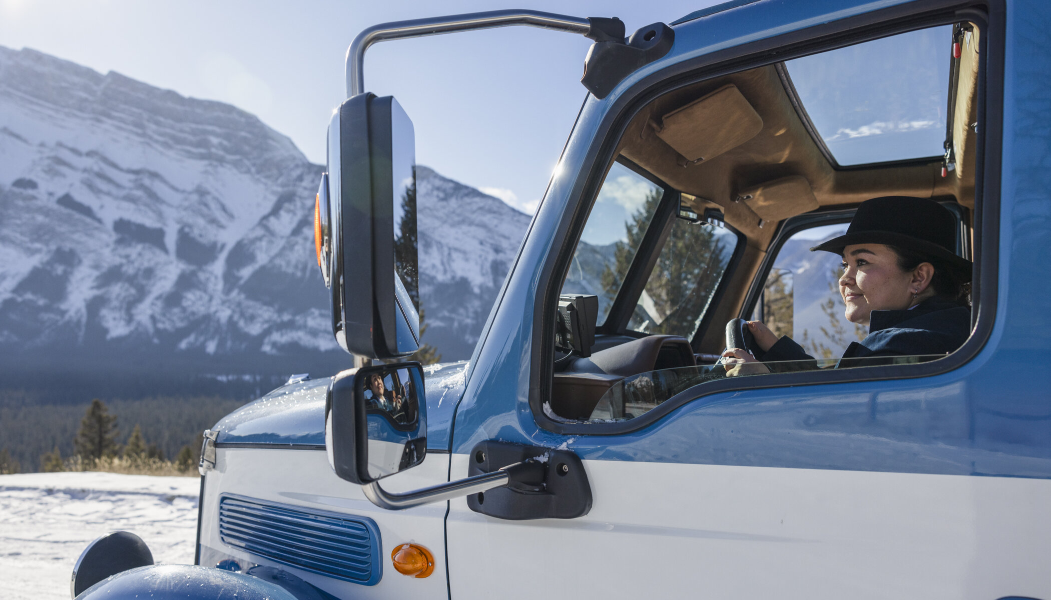 A guide driving the open top tour bus around Banff