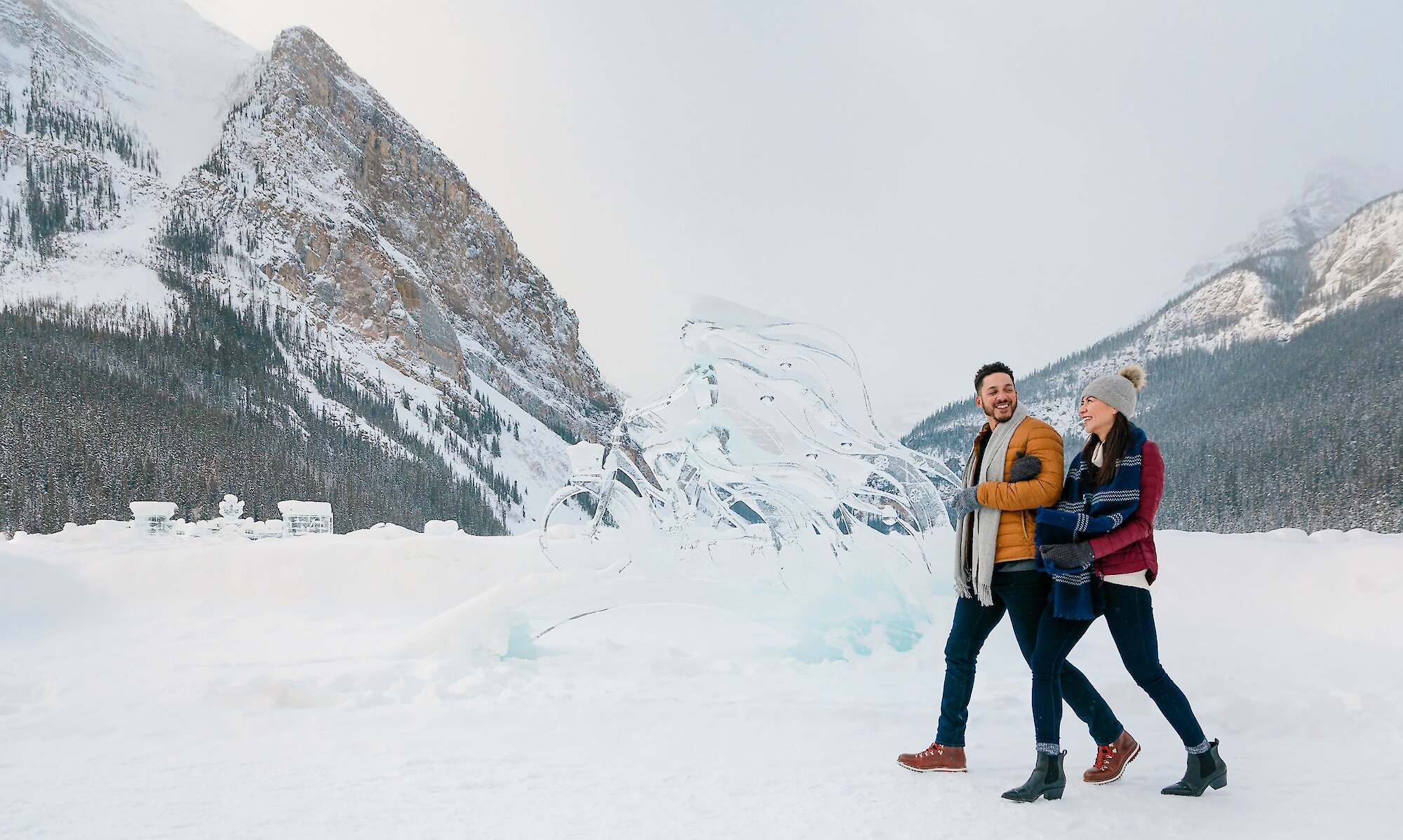 A couple walking along Lake Louise lake shore with the ice sculptures.