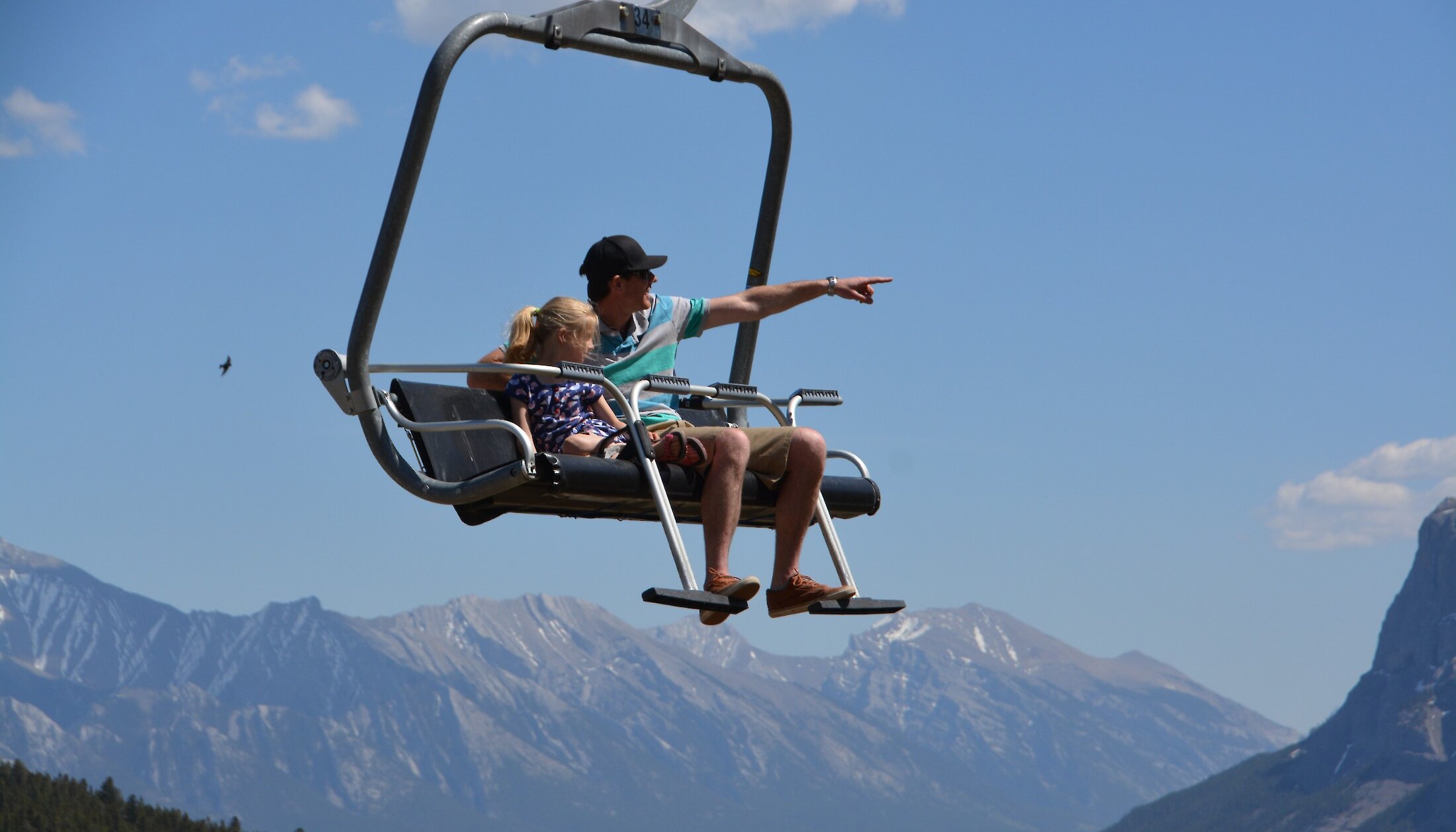 A little girl being held by her dad looking through a tower viewer on the Banff Gondola viewing deck