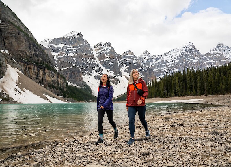 Two women walking along the shoreline of Moraine Lake