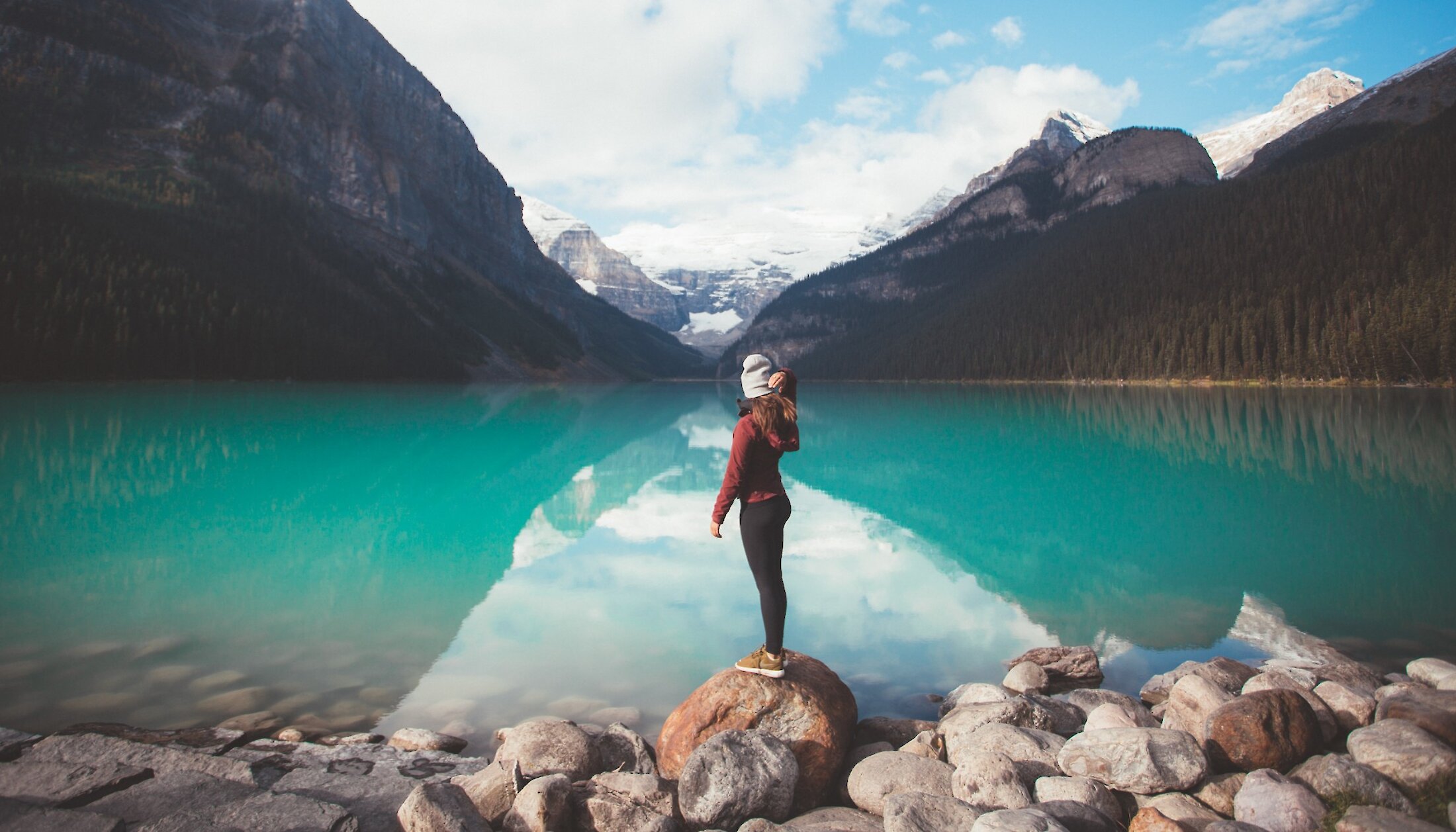 A woman standing on Lake Louise Shorline looking at the Victoria Glacier