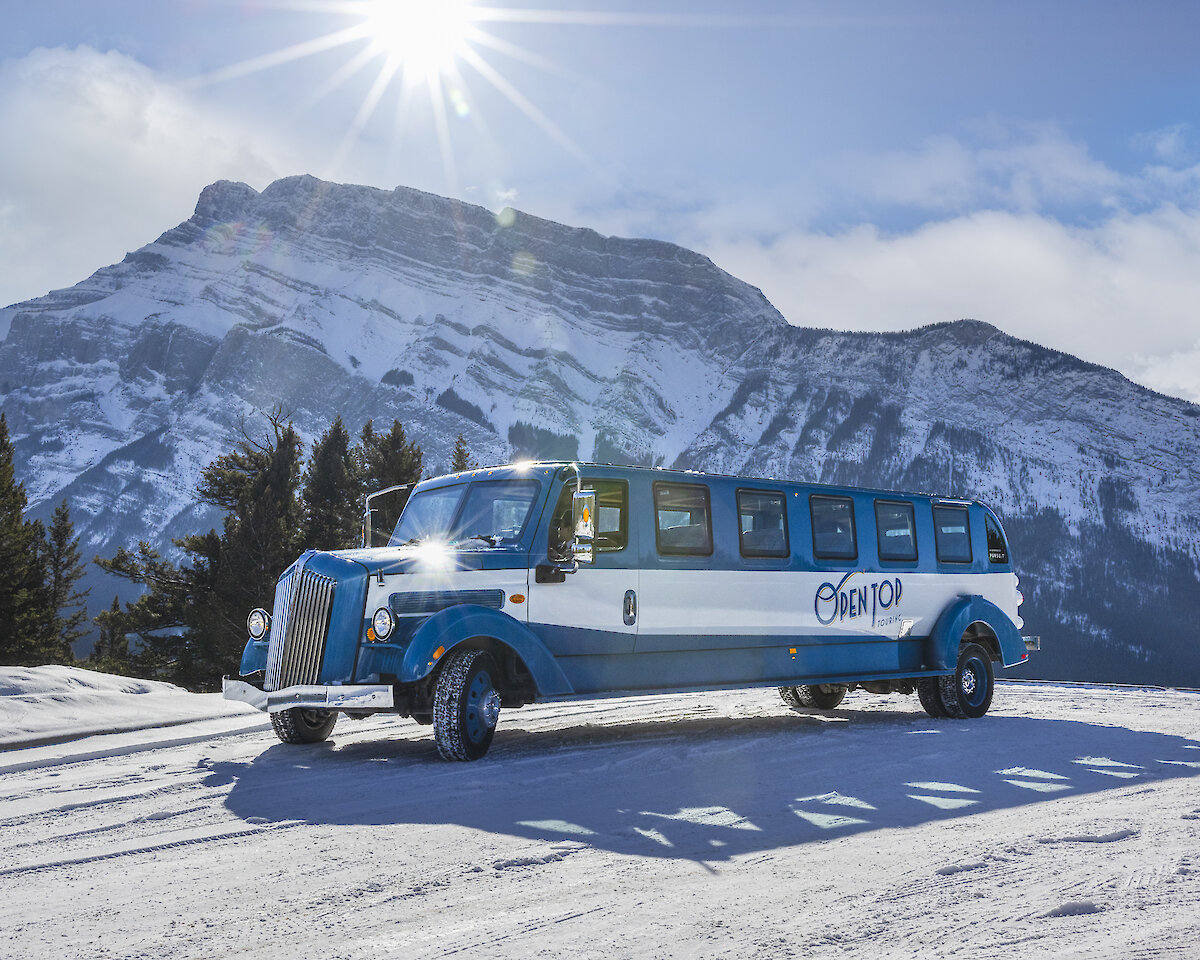 A view of the open top tour bus with Rundle Mountain in Banff National Park