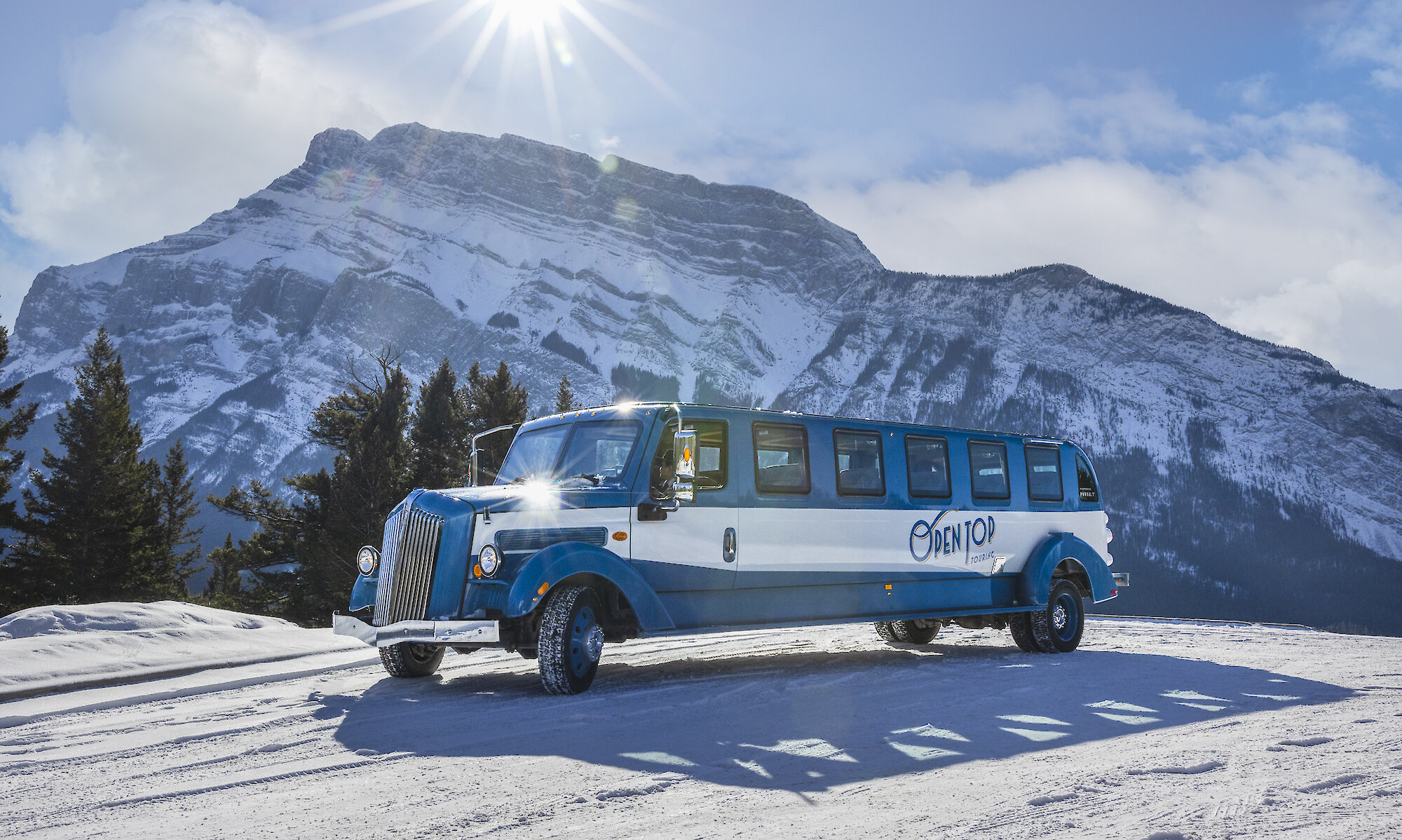 A view of the open top tour bus with Rundle Mountain in Banff National Park